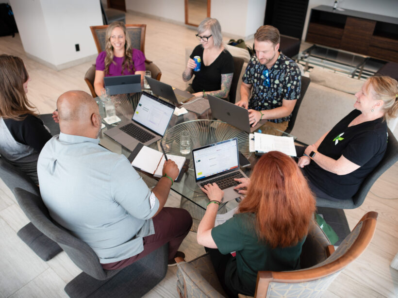 Aerial shot of Kanopi leadership around a table working on a project with laptops open.
