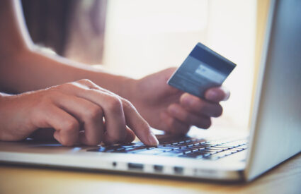 Hands holding credit card and using laptop. Online shopping