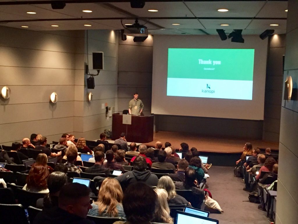 Image of Kanopian Paul Sheldrake speaking on Pattern Lab in Drupal 8. It's a large room with lots of seating facing a large projector screen.