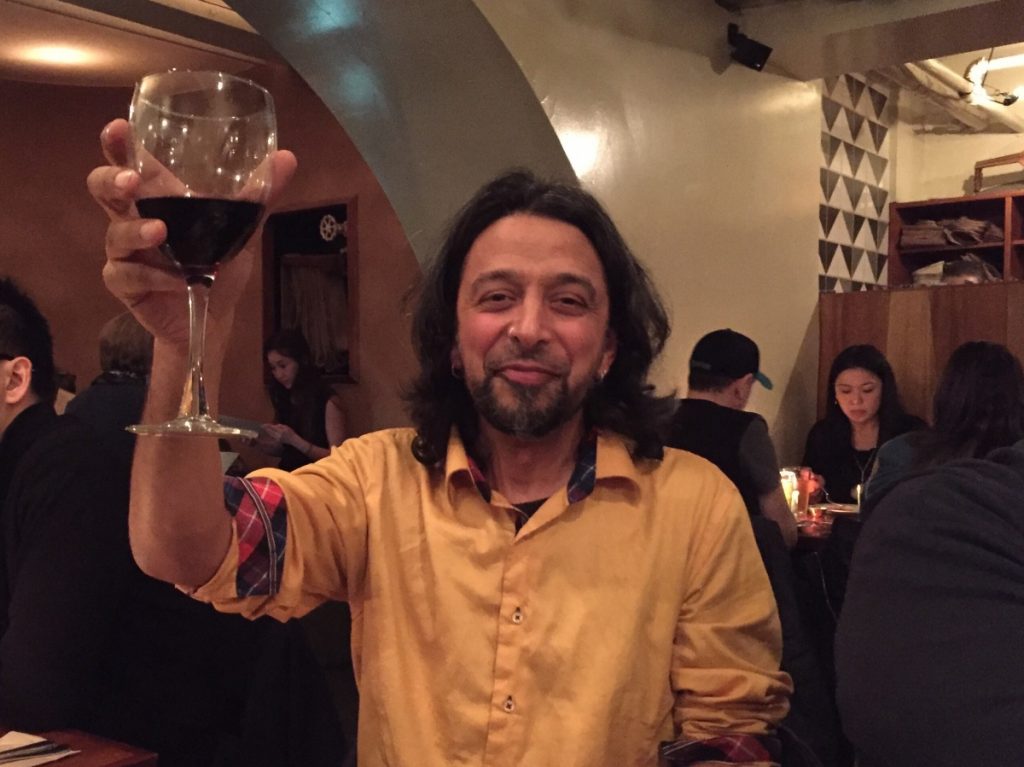 Shiraz Dindar of Kanopi raising a glass of wine in a toast at dinner. 