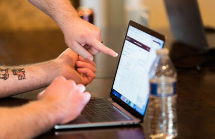 Hands pointing to a laptop