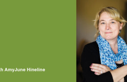 Image of AmyJune Hineline for her Accessible Media webinar. She has a blue scarf and her arms are folded.