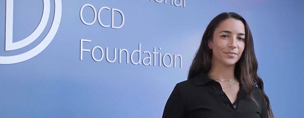 Olympic gymnast Aly Raisman in front of a wall on which the IOCDF logo is displayed