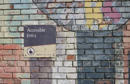 A colourful brick wall with a sign directing customers to an accessible entry.