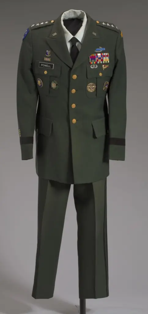 U.S. Army green service uniform worn by Colin L. Powell as General and as Chairman of the Joint Chiefs of Staff. Uniform is hanging on a pole facing forward.