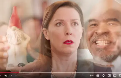 A screenshot from the Radical Candor video, featuring a woman in the center looking confused, with a gnome figurine on the left, and her male boss smiling on the right.