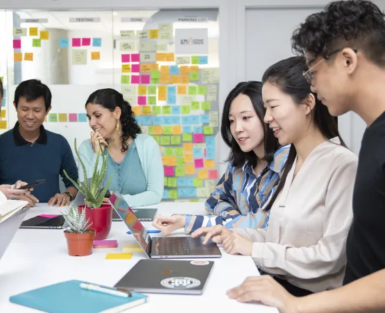 Five Centre for Digital Media students working at a desk surrounded by sticky notes and notebooks