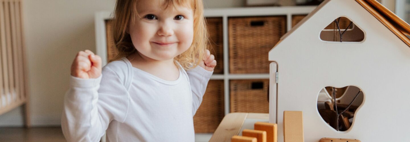 Photo by Tatiana Syrikova of a white toddler smiling while playing with toys