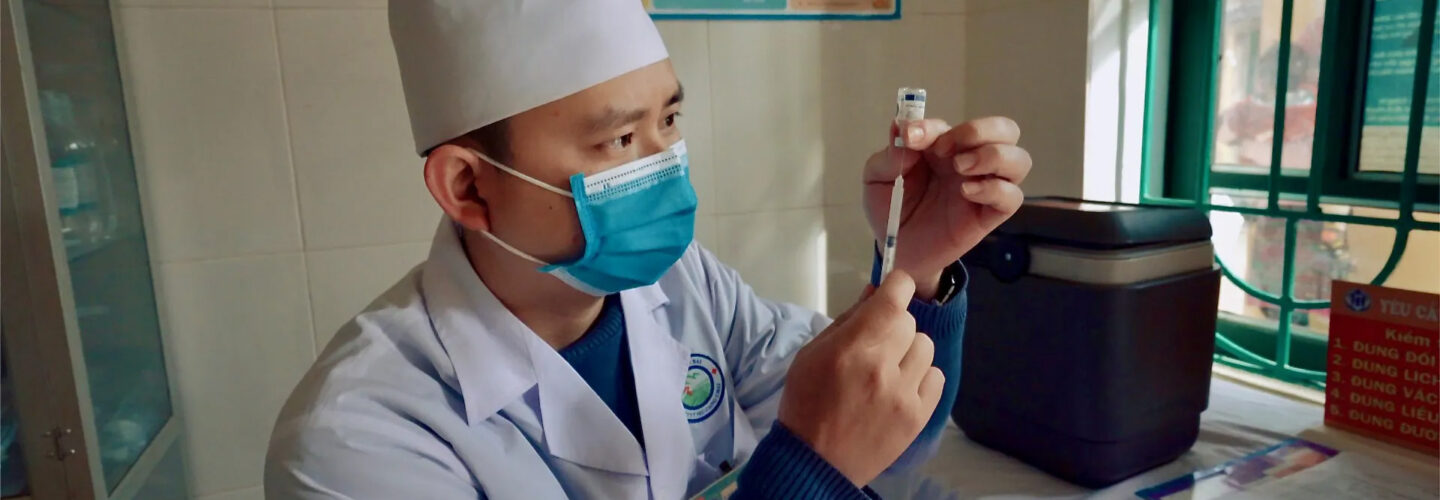 A physician pulling liquid out of a bottle with a syringe