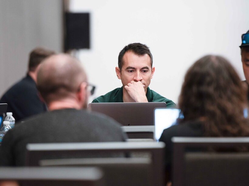 A focused Kanopi Studios team working together on laptops during a collaborative strategy session, developing digital solutions and creative strategies for clients.
