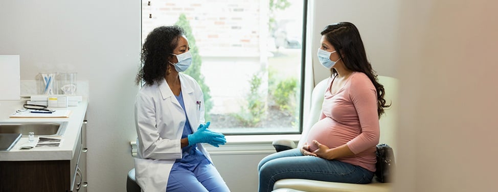 A female doctor talks to her pregnant patient.