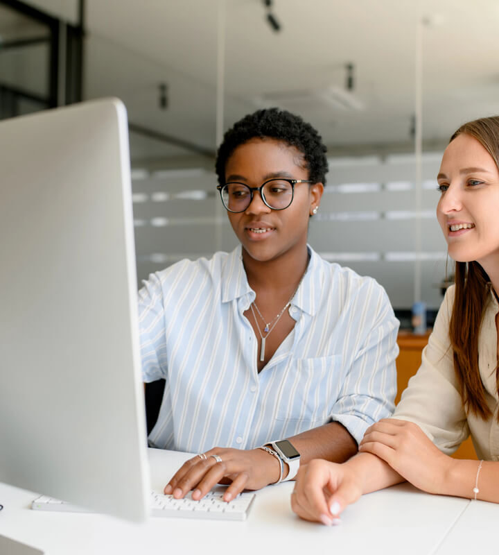 Two association professionals look at a desktop computer in an office