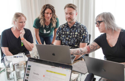 Denise, Jill, Tim and Erin from Kanopi leaning over a laptop to review what's on the screen.