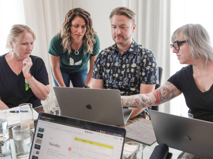 Denise, Jill, Tim and Erin from Kanopi leaning over a laptop to review what's on the screen.