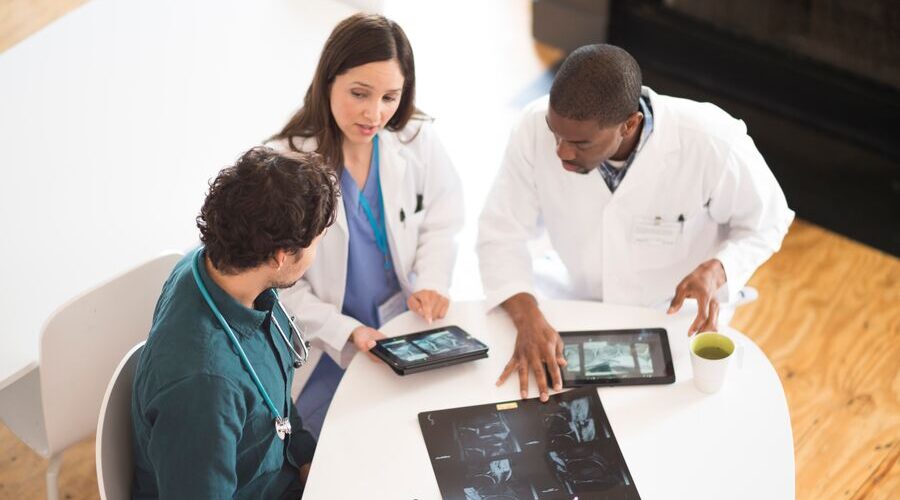 Arial shot of three doctors reviewing medical scans on their tablets