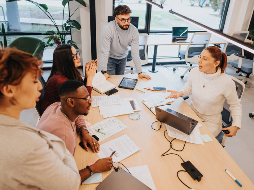 A diverse group of marketing professionals meets at a large conference table to discuss strategy